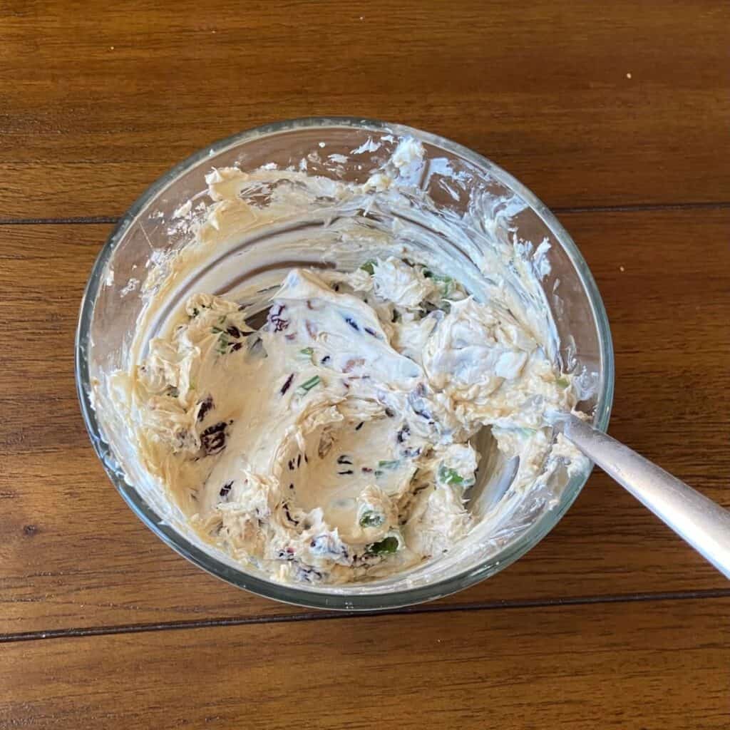 Cream cheese, goat cheese, cranberries, pecans, and green onion mixed in a bowl.